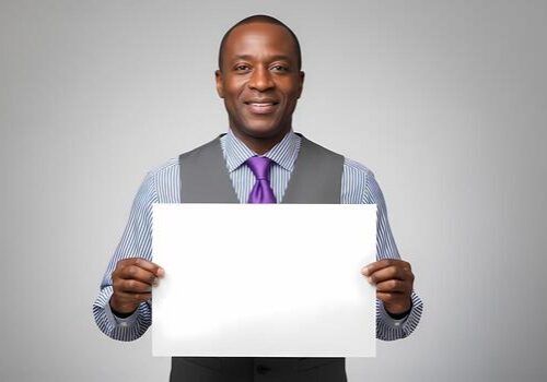 smiling-black-man-in-business-attire-holding-blank-white-sign-board-studio-portrait-advertisement-photo